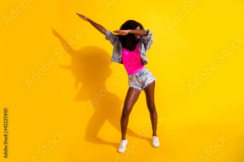 Full body photo of funky afro american lady dance dab weekend wear jeans jacket isolated on shine yellow color background photo