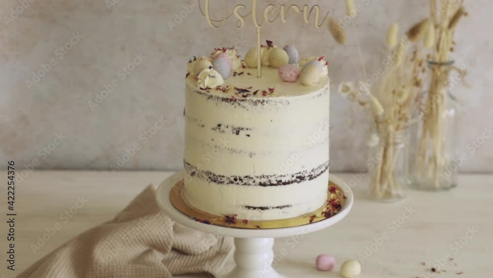 A 4K shot of a delicious Easter Frohe Ostern Naked Cake on a white decorated table