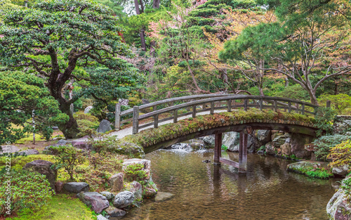 Japanese garden in Kyoto, authentic wooden bridge over the river, spruce and pine trees. Calm and tranquility.