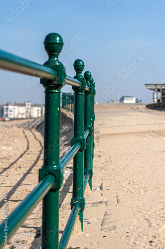 Beach front railings, separating the concrete path or sea wall, from the sandy beach of Margate in Kent