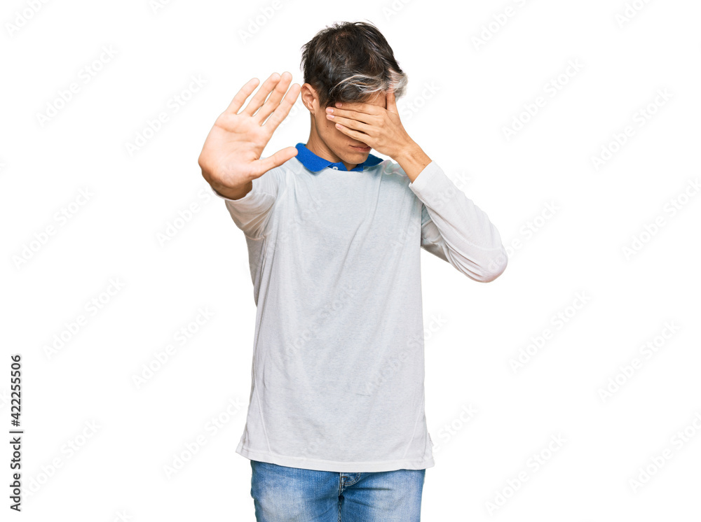 Young hispanic man wearing casual clothes covering eyes with hands and doing stop gesture with sad and fear expression. embarrassed and negative concept. Young hispanic man wearing casual clothes covering eyes with hands and doing stop gesture with sad and fear expression. embarrassed and negative concept.