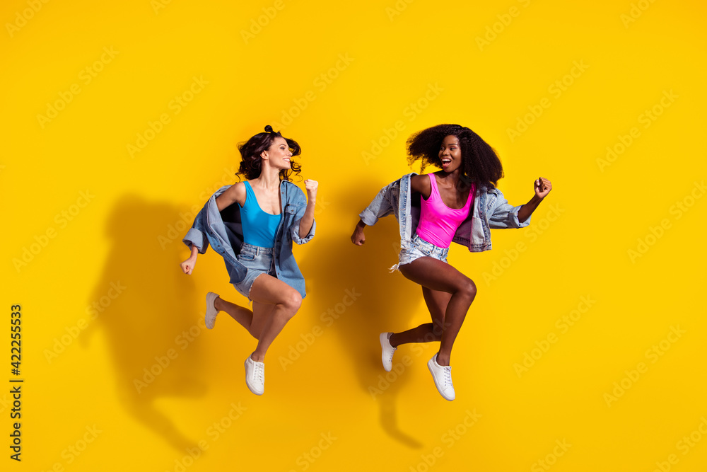 Full size photo of brunette attractive woman jump up run sale wear jeans jacket shorts singlet isolated on yellow color background