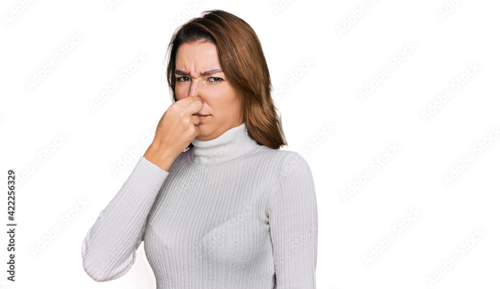 Young caucasian girl wearing casual clothes smelling something stinky and disgusting, intolerable smell, holding breath with fingers on nose. bad smell Young caucasian girl wearing casual clothes smelling something stinky and disgusting, intolerable smell, holding breath with fingers on nose. bad smell