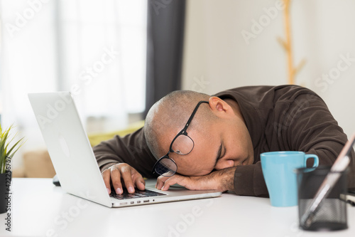 The young man was working in front of the laptop, he was tired. And fell asleep on the desk He needs rest