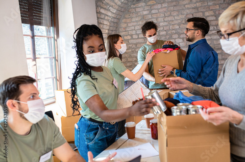 Group of volunteers with face mask working in community charity donation center. photo