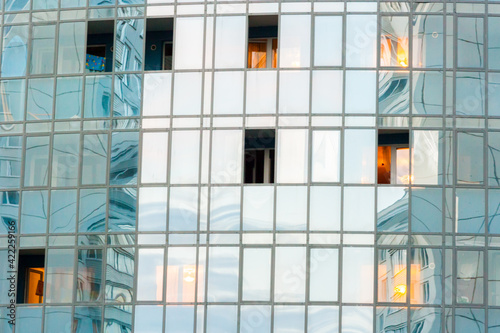 Blue modern ventilated facade with windows. Fragment of a new elite residential building or commercial complex. Part of urban real estate. Clouds reflected in windows. Photo with copy space