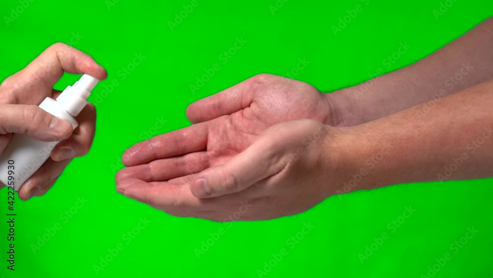 Disinfectant Antibacterial Agent is Applied to Male Hands on a Green Background. An Elderly Male Hand Applies to Another Person's Young Male Hands Spray to Protect Hands from Viral Diseases. Disinfectant Antibacterial Agent is Applied to Male Hands on a Green Background. An Elderly Male Hand Applies to Another Person's Young Male Hands Spray to Protect Hands from Viral Diseases.