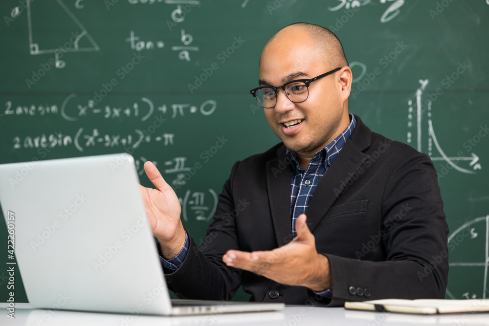 Indian young teacher man sitting teaching online video conference live stream by laptop. Asian teacher teaching mathematics class webinar online for students learning.