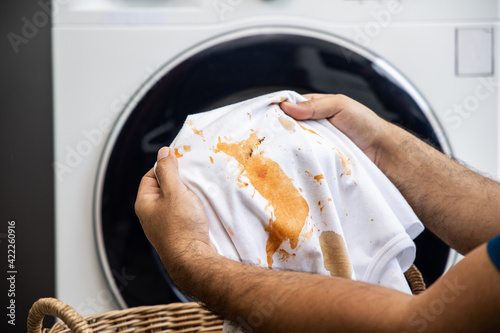 White cotton shirt A lot of stains, stains, coffee stains, man's hand holds the shirt up and spreads it to look dirty Must be brought to the washing machine