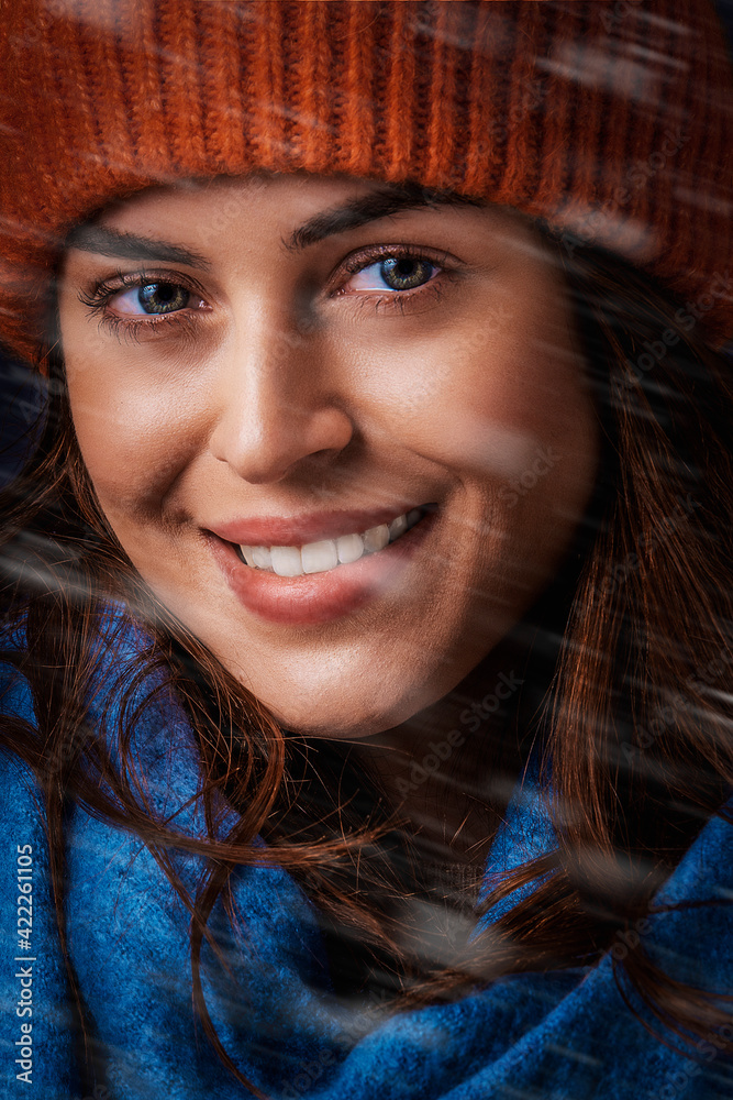 Close-up portrait of a young woman in winter clothes while falling snow Close-up portrait of a young woman in winter clothes while falling snow
