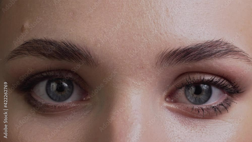 A young woman opens her eyes and looks into the camera. Extreme close-up.