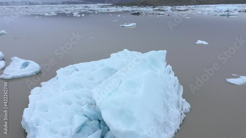 Flying over floating icebergs in Fjallsarlon glacial lagoon, Iceland. Aerial view of melting ice cap as result of global warming and climate change photo