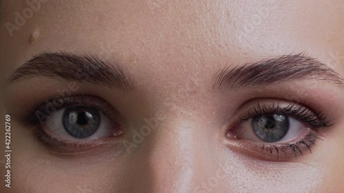 A young woman opens her eyes and looks into the camera. Extreme close-up. photo