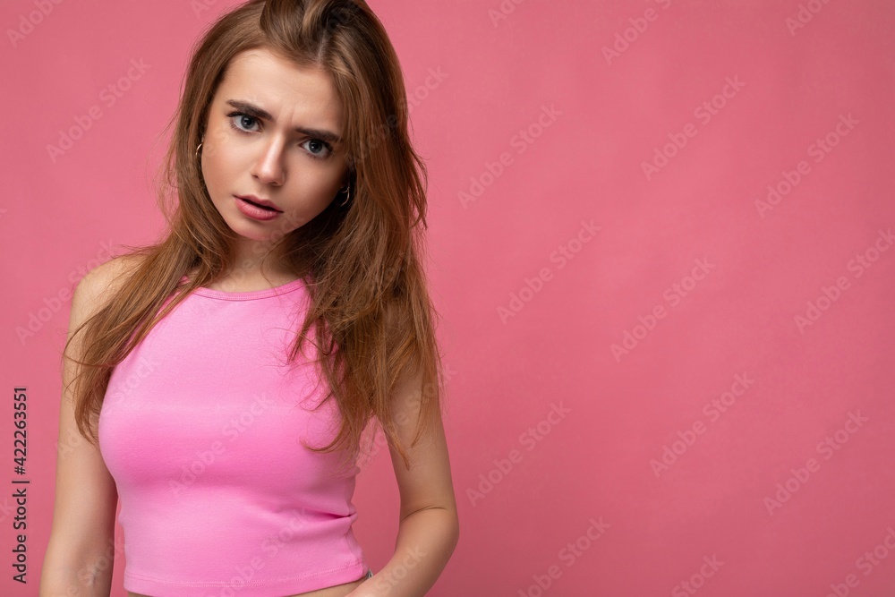 Sad upset young beautiful dark blond woman isolated on background with copy space wearing stylish pink top. Negative concept Sad upset young beautiful dark blond woman isolated on background with copy space wearing stylish pink top. Negative concept