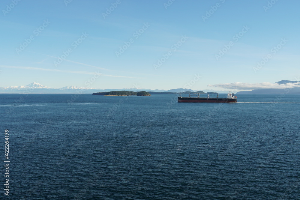 View form the container ship on another cargo ship with mountain covered with snow in background during approaching to Vancouver, British Columbia, from Pacific ocean.
