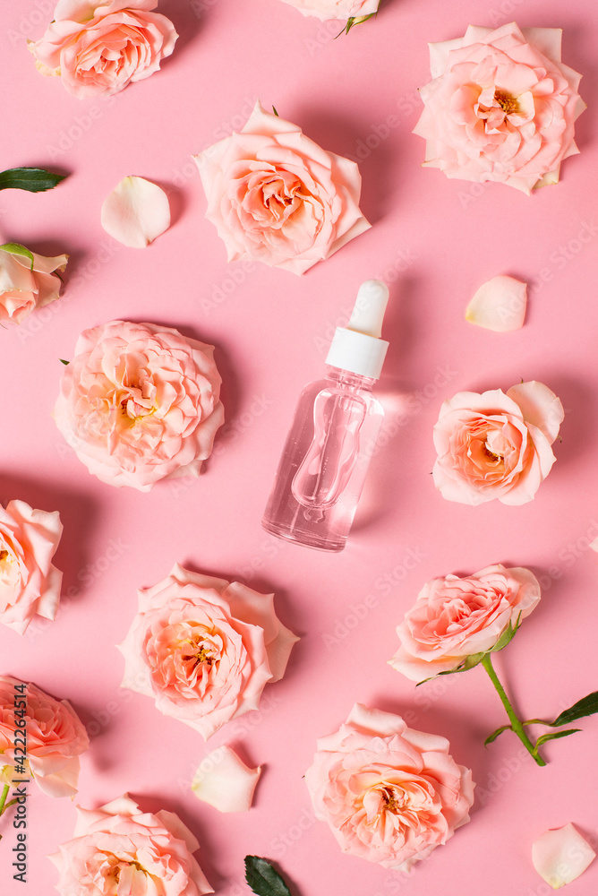 Plakat Bottles of serum with rose flowers flat lay on pink background