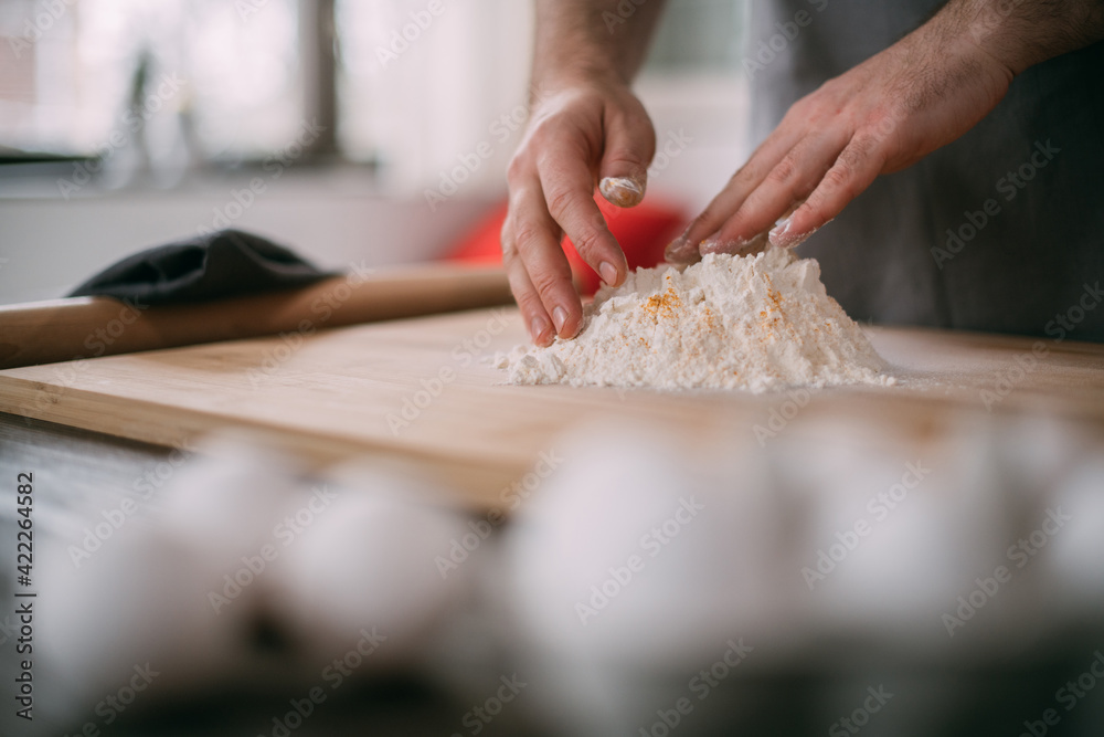 A male chef prepares noodle dough at home in the kitchen. Close up of hands with flour and dough A male chef prepares noodle dough at home in the kitchen. Close up of hands with flour and dough