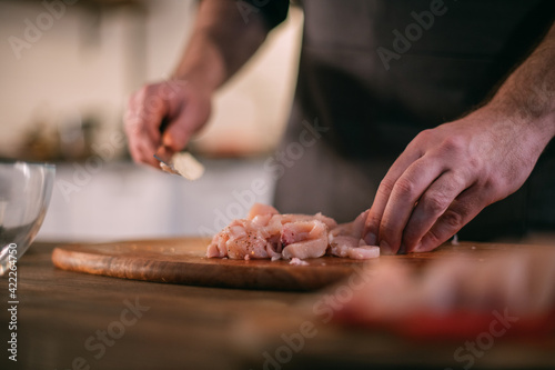 A male chef prepares fresh meat at home in the kitchen..