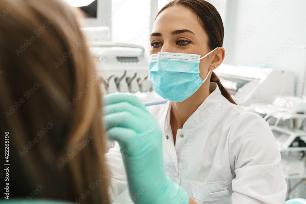 European mid dentist woman in face mask working in dental clinic European mid dentist woman in face mask working in dental clinic