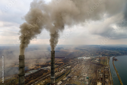 Aerial view of coal power plant high pipes with black smoke moving up polluting atmosphere.