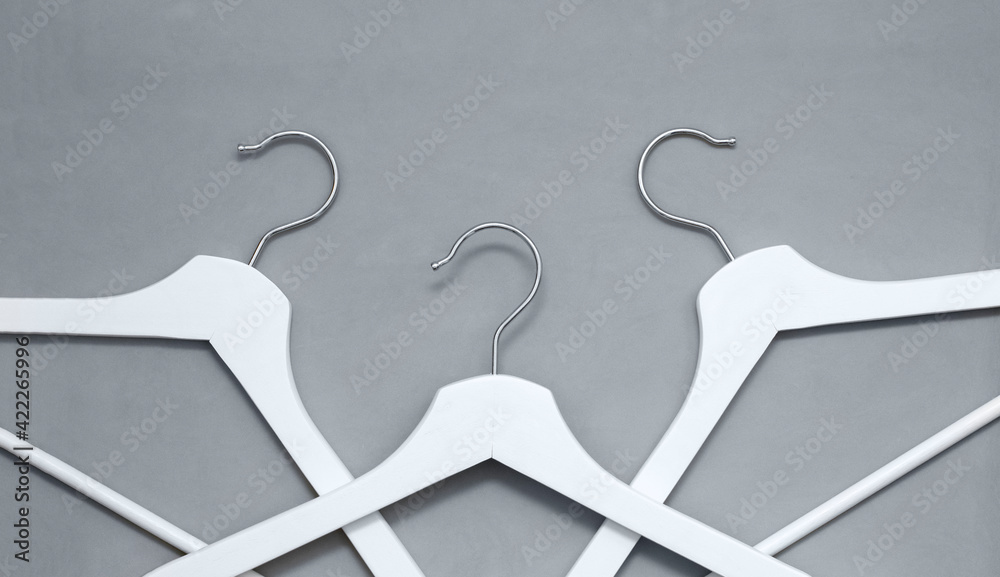 Creative top view flat lay white wooden hangers pastel grey background with copy space minimalism style. Template fashion social media sale store promo design feminine blog shopping concept Creative top view flat lay white wooden hangers pastel grey background with copy space minimalism style. Template fashion social media sale store promo design feminine blog shopping concept