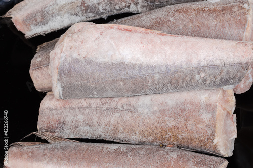 Top view of frozen Argentine hake carcasses on black plate