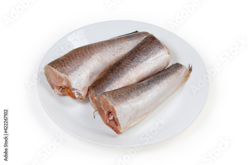 Obraz na plátně Defrosted uncooked Argentine hake carcasses on a white dish
