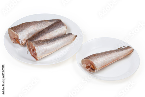 Defrosted uncooked Argentine hake carcasses on a white dishes