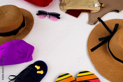 Passport in a belt bag. Flip flops, safety goggles and straw hat, airplane inflatable pillow, sleep mask and earplugs for flight, travel swimwear with copy space