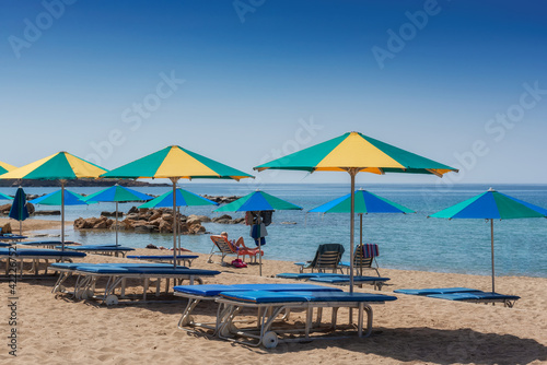 Beach umbrellas and sunbeds on sandy Coral beach in Paphos, Cyprus. 