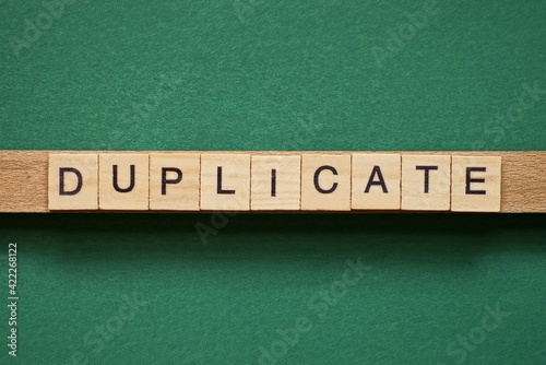 gray word duplicate made of wooden square letters on green background