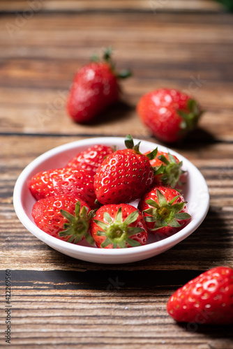 Fresh strawberries in a plate on wooden table
