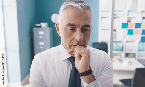 Pensive businessman thinking with hand on chin