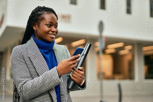 Young african american businesswoman smiling happy using smartphone at the city.