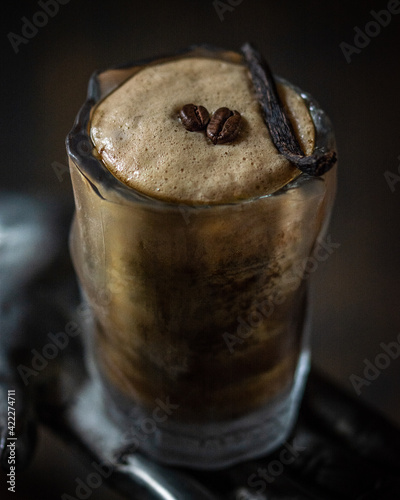 dettaglio di cocktail al caffè con decorazione con schiuma d'uovo, chicchi di caffè e bacca di vaniglia photo