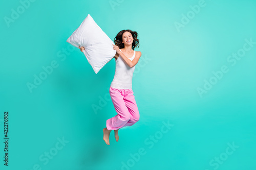 Full length photo of pretty shiny young woman sleepwear fighting pillows isolated turquoise color background