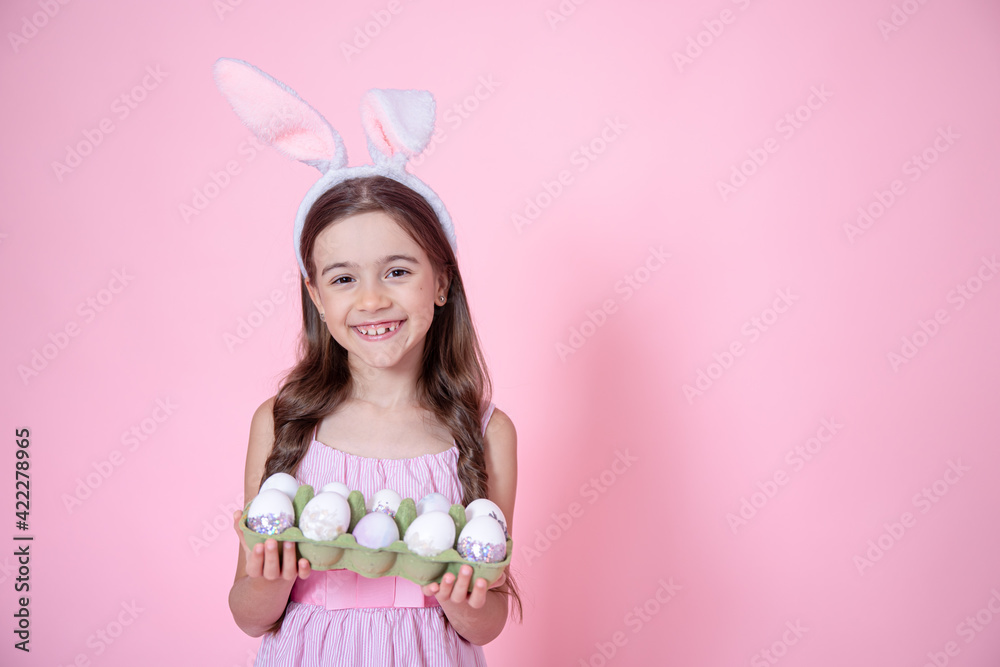 Cute little girl with easter bunny ears and a tray of easter eggs copy space.