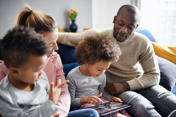 Multi ethnic family with two small children using tablet at home.