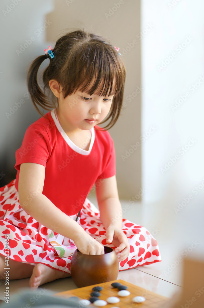 little cute asian girl focusing to play on her baduk (GO) board game little cute asian girl focusing to play on her baduk (GO) board game