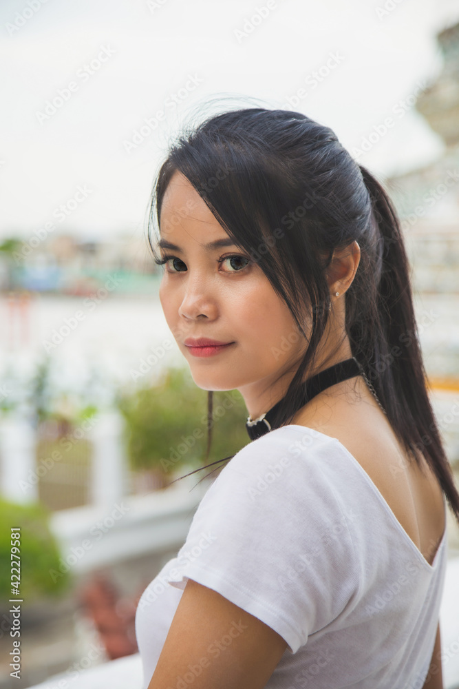 Portrait beautiful Asian woman in a white T-shirt looking at a camera at the Wat Arun temple while traveling in Thailand.