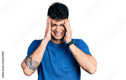 Young hispanic man wearing casual t shirt with hand on head, headache because stress. suffering migraine.