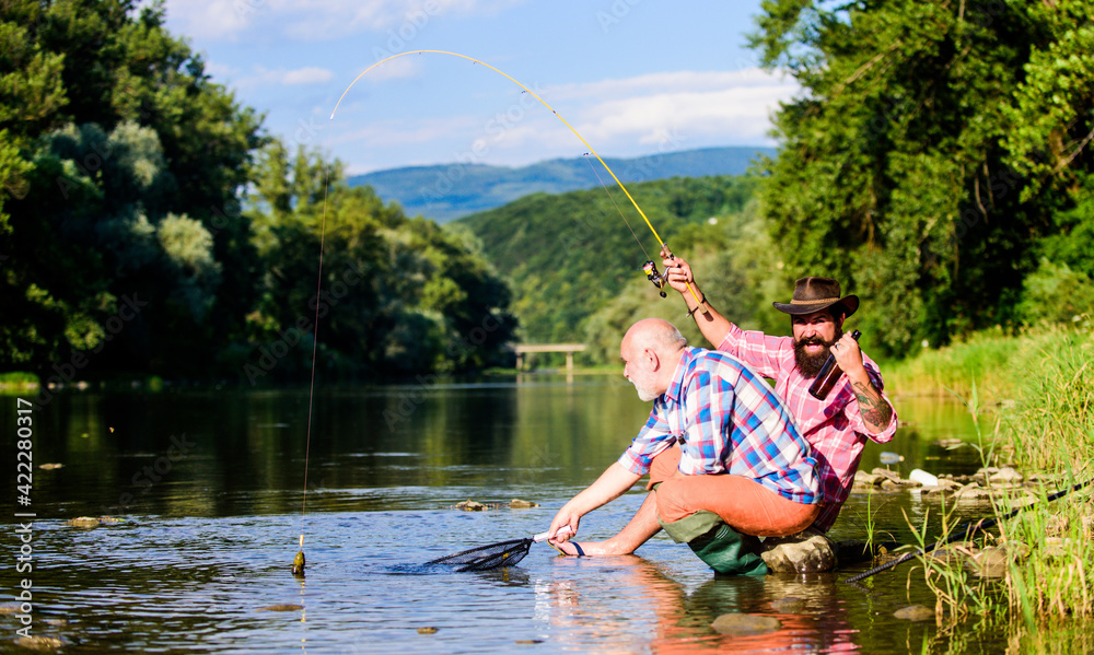 Fishing activity concept. retired dad and mature bearded son. big game fishing. happy fishermen friendship. Two male friends fishing together. fly fish hobby of men. retirement fishery Fishing activity concept. retired dad and mature bearded son. big game fishing. happy fishermen friendship. Two male friends fishing together. fly fish hobby of men. retirement fishery
