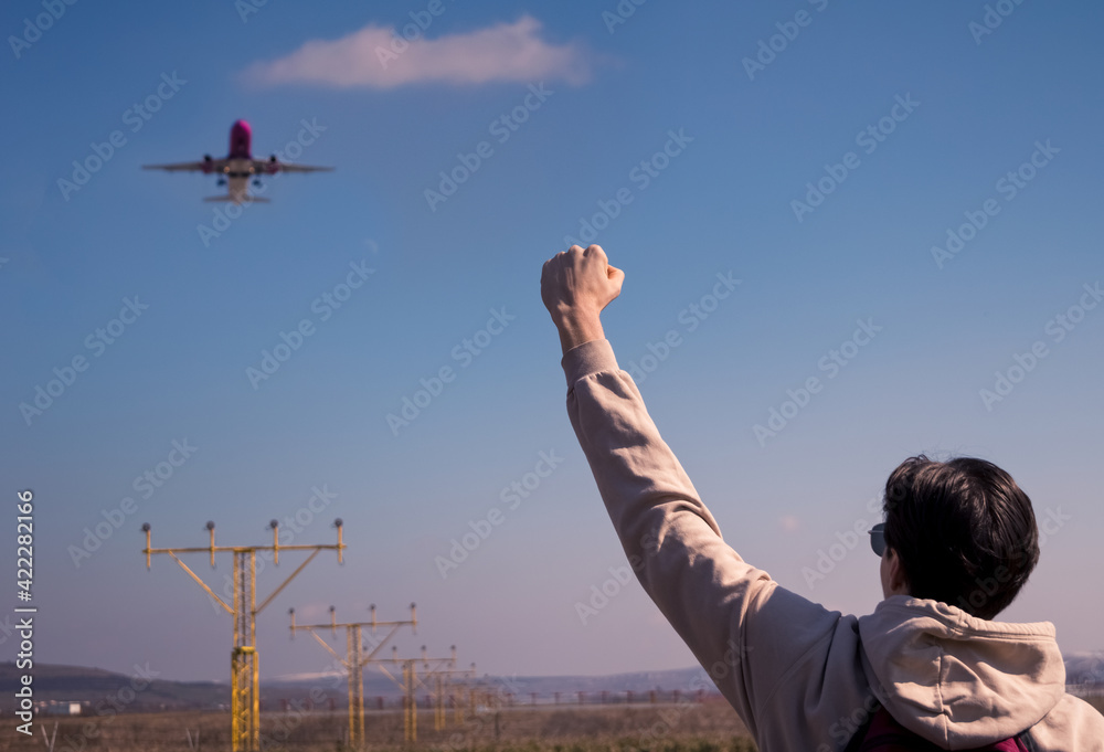 Back view of Young man with his hand raised on the airport runway