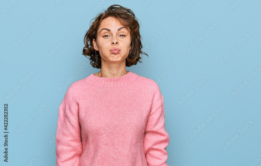 Young hispanic woman wearing casual clothes puffing cheeks with funny face. mouth inflated with air, crazy expression. Young hispanic woman wearing casual clothes puffing cheeks with funny face. mouth inflated with air, crazy expression.