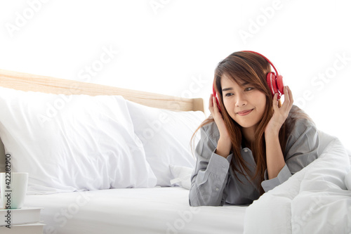 Young beautiful asian 20s woman relaxing in the bed, listening to music with neadphone and lying down. Concept of relax time, enjoyment, rest and happy