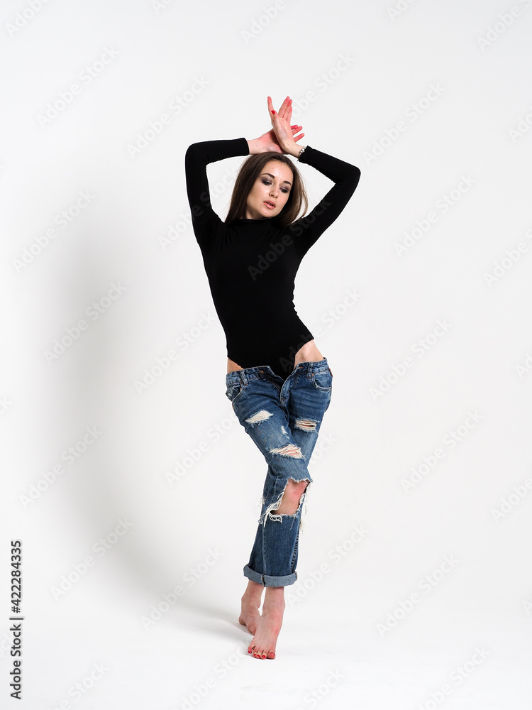 The brunette on a white background in a bodysuit and jeans with heels The brunette on a white background in a bodysuit and jeans with heels