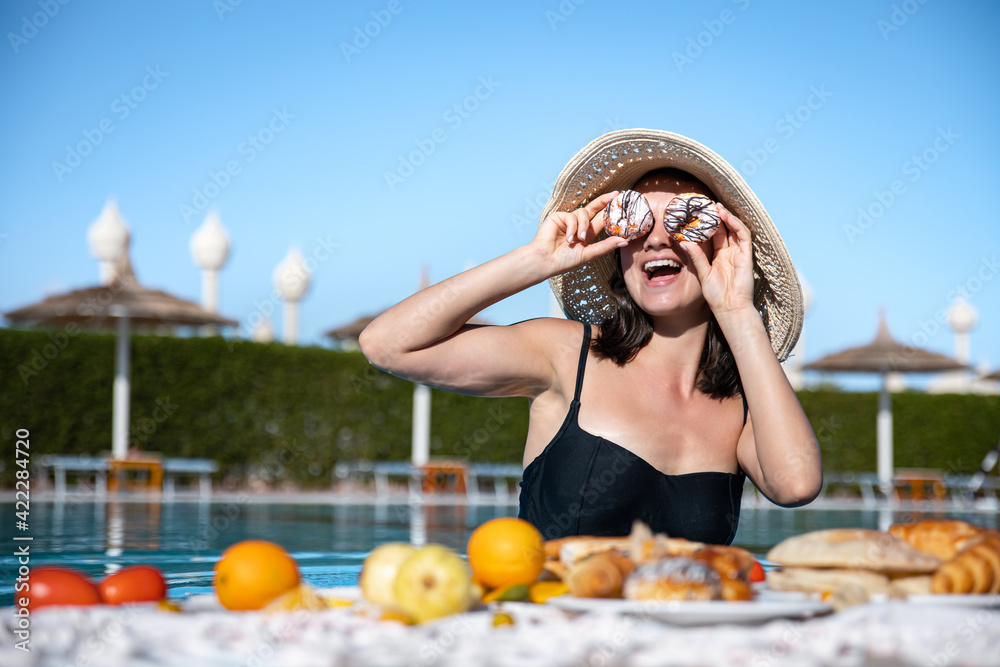 Fototapeta premium Attractive girl enjoying a delicious breakfast in the pool at the resort.