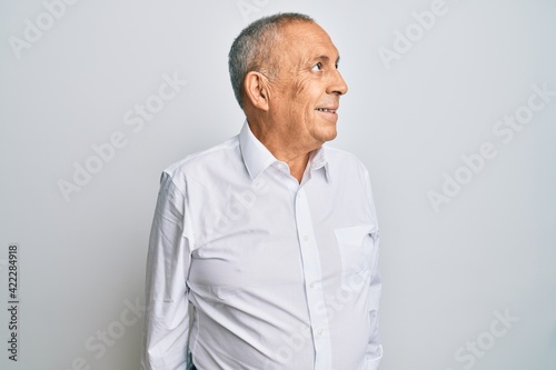 Handsome senior man wearing casual white shirt smiling looking to the side and staring away thinking.