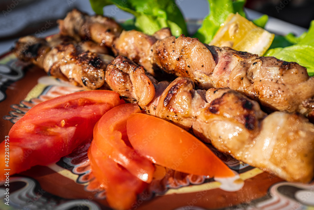 BBQ chicken skewers with tomatoes and lettuce salad. close up.