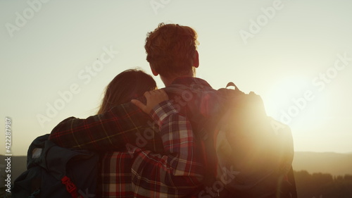 Romantic couple enjoying sunset in mountains. Woman and man hugging each other